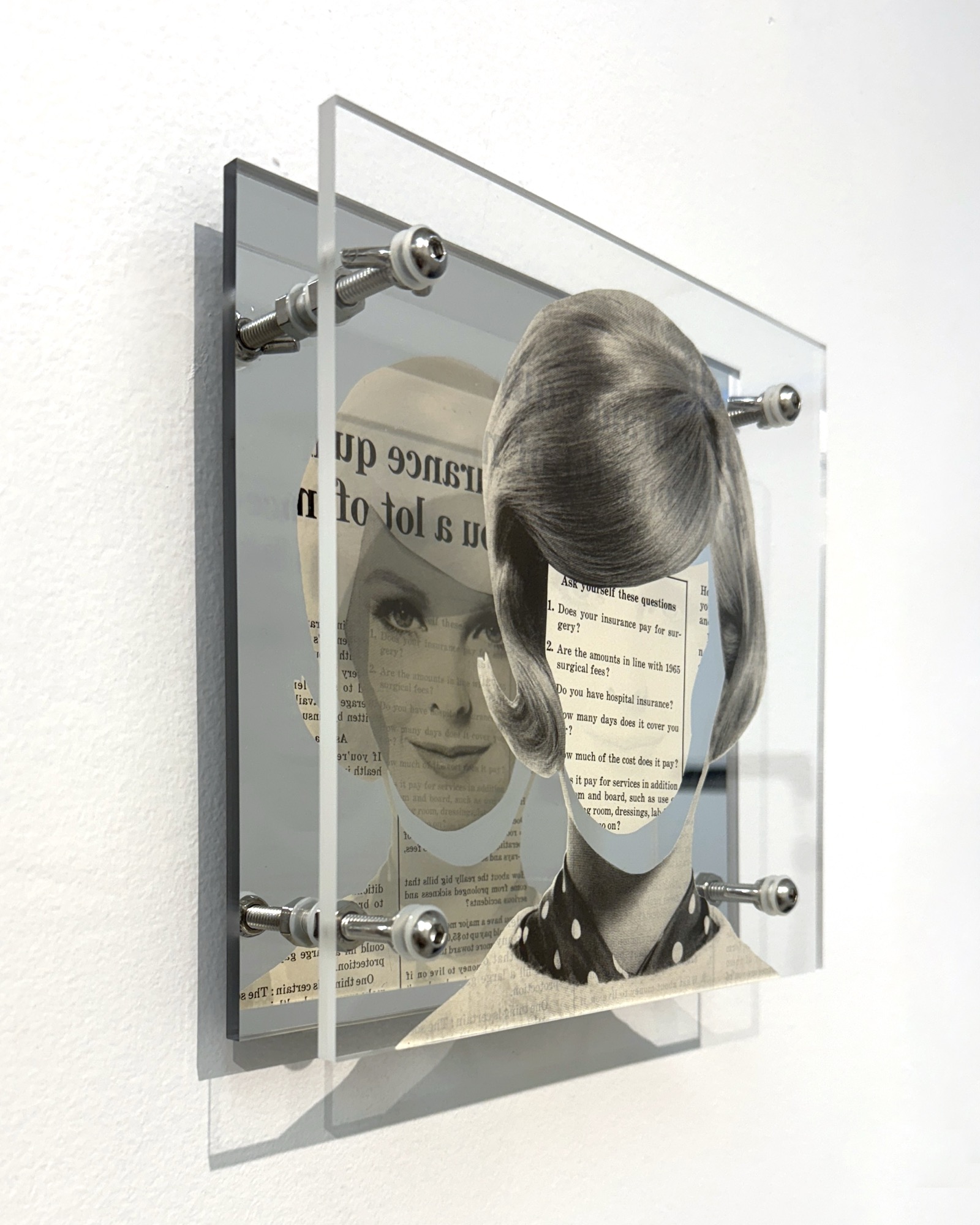Coverage by Shannon Milar — Double Take series. Found images, clear + mirrored acrylic, nylon + metal hardware. A woman with a tall bouffant hairstyle, her face replaced by a cutout exposing insurance text through the printed page, the mirror returning both sides at once.