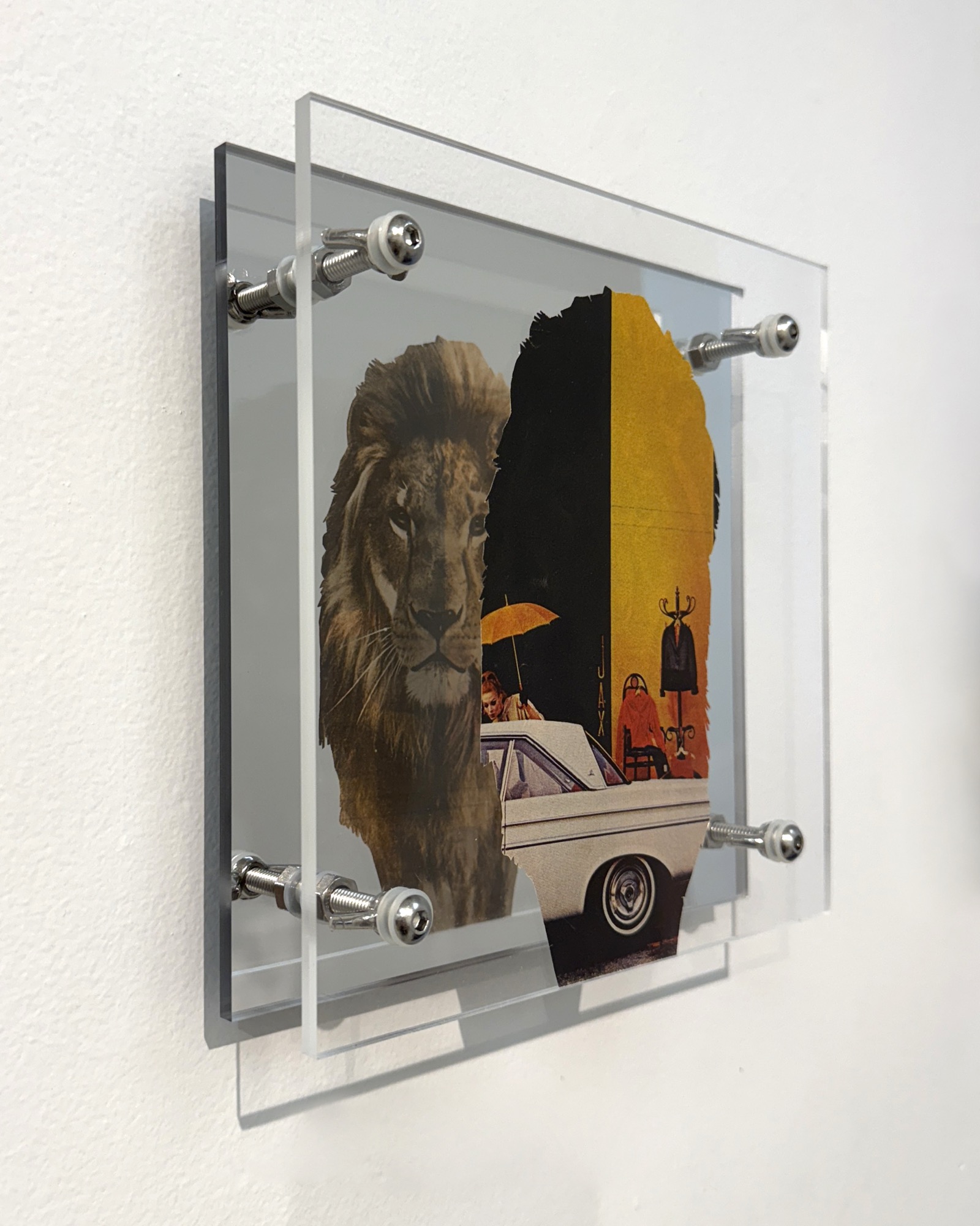 Power by Shannon Milar — Double Take series. Found images, clear + mirrored acrylic, nylon + metal hardware. A lion's head merges with a dark silhouette against a bold yellow and black ground, a vintage car visible below, the mirror compressing image and reflection into a single field.